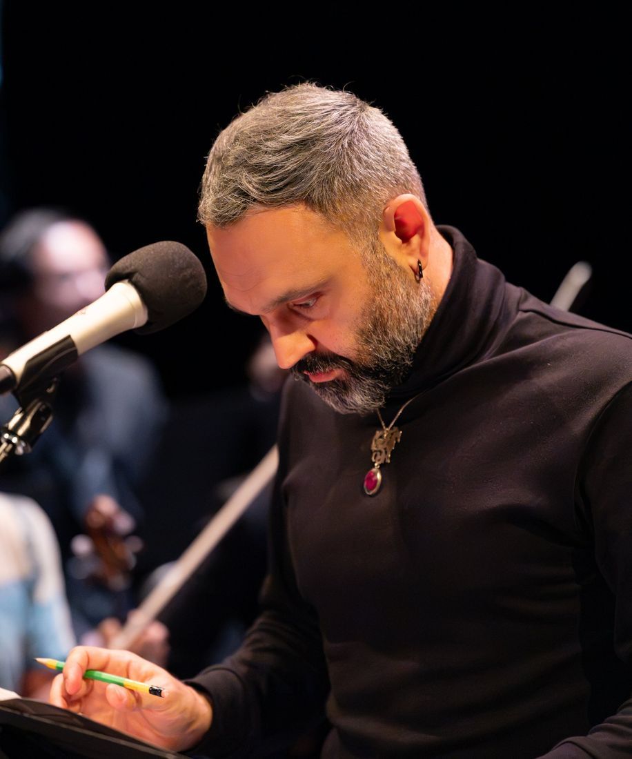 Milad Bagheri at the microphone, reading a score